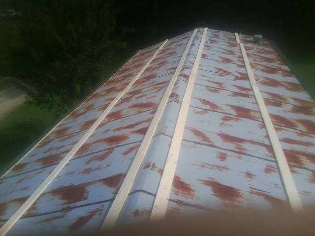 Rusted metal roof panels with new wood purlins before replacement — Storm Damage Roof Repair in Shenandoah by Roofing Brothers