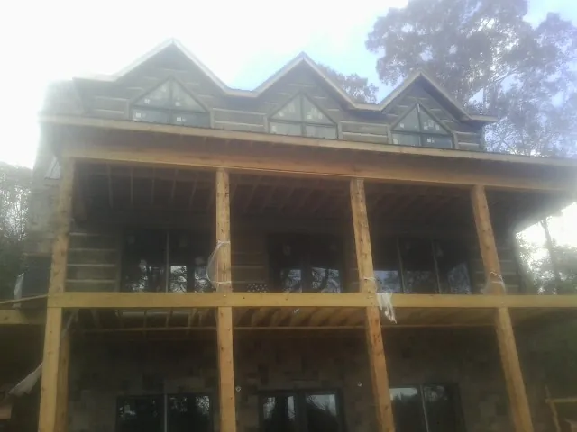 Dormers and porch framing on a large log home under construction — Roof Coating work by our crew in Shenandoah