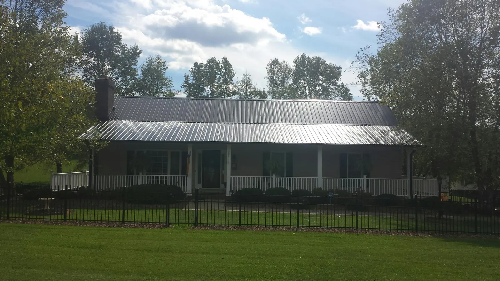 Gray metal roof on a brick ranch with a full width front porch — Gutter Guard Installation work by our crew in Shenandoah